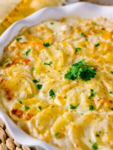 Close-up of a potato casserole in a white dish, showcasing its creamy texture and golden-brown top. Taste of Home Recipes.