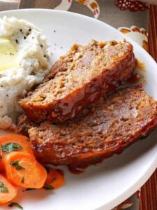 A delicious meatloaf served with creamy mashed potatoes and vibrant carrots, inspired by Taste of Home Recipes.