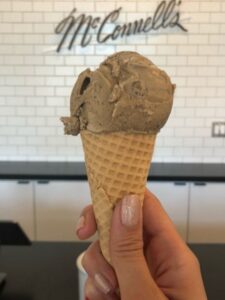 A person joyfully holds a chocolate ice cream cone, showcasing the best ice cream treat on a sunny day.